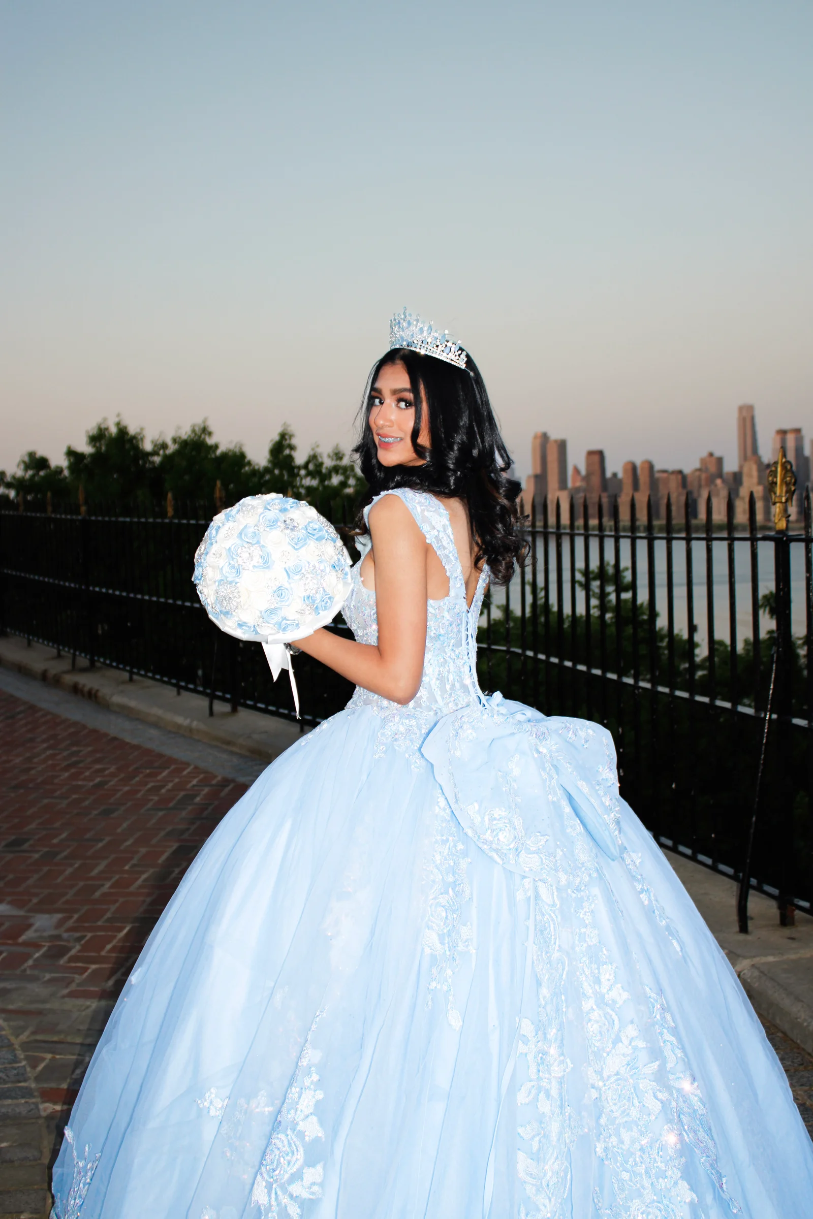 The celebrant looking back with a bouquet against a distant city skyline