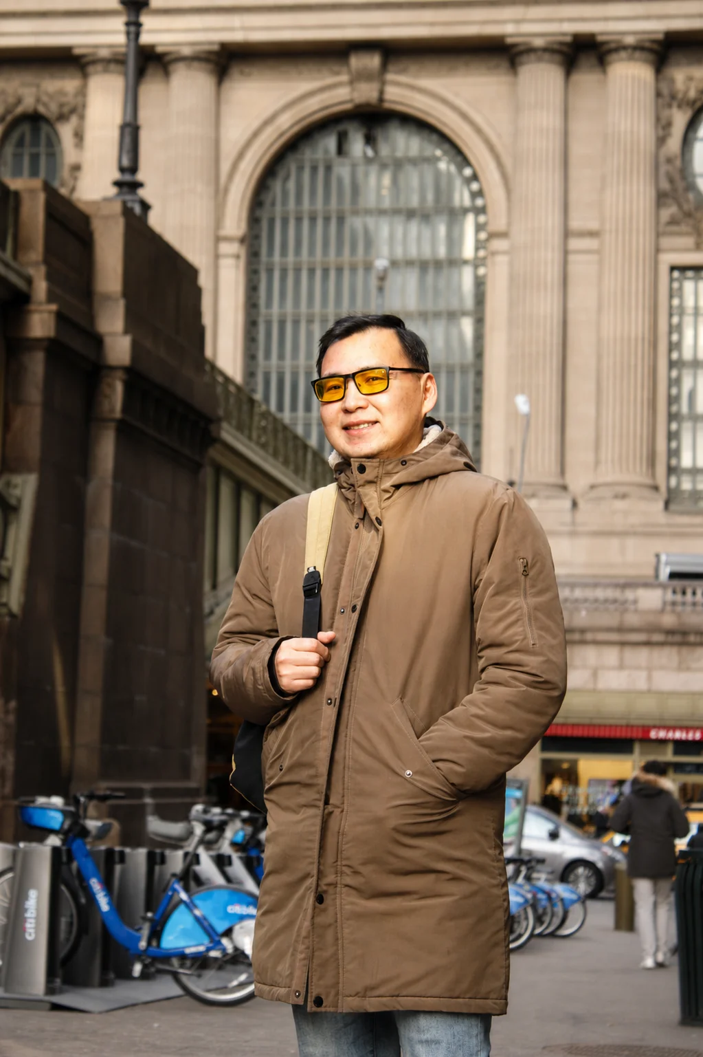 A portrait in a brown coat and sunglasses outside Grand Central Terminal