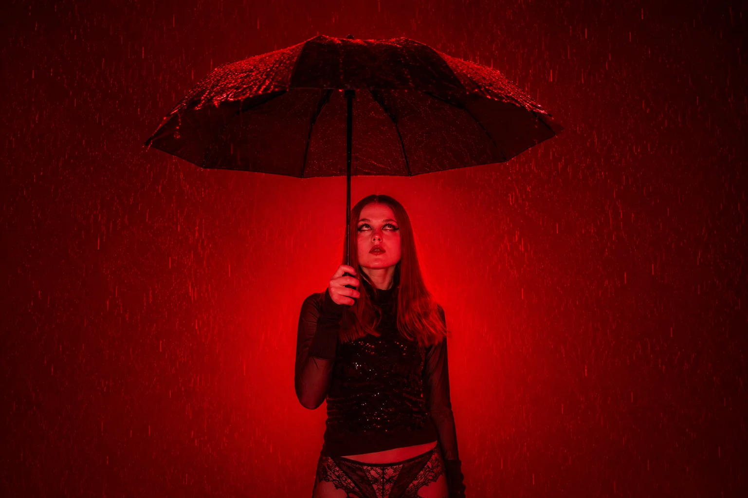 An editorial portrait beneath an umbrella illuminated with red light
