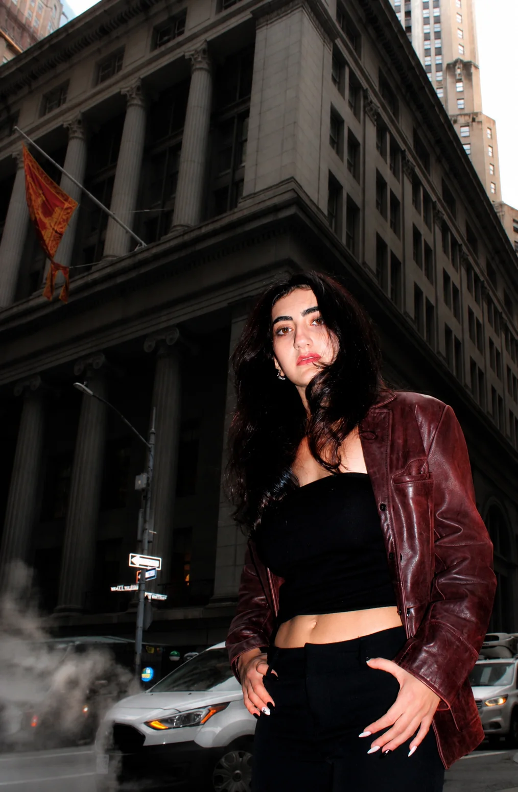 A portrait in a burgundy jacket beneath stone building columns