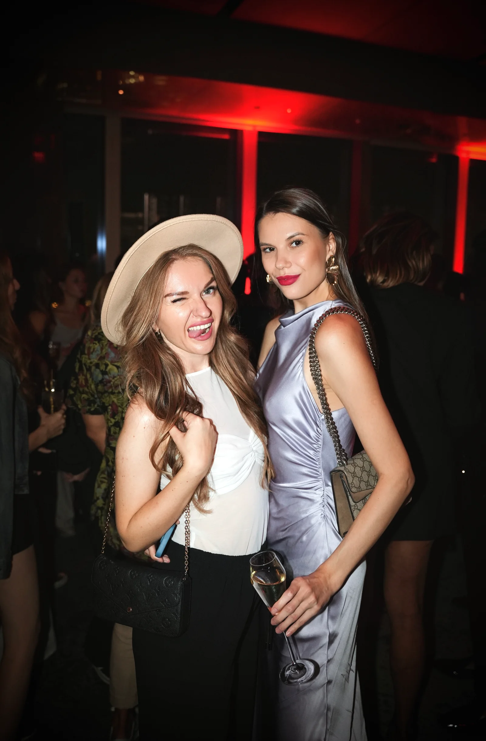 Two guests in party outfits posing together at an evening celebration