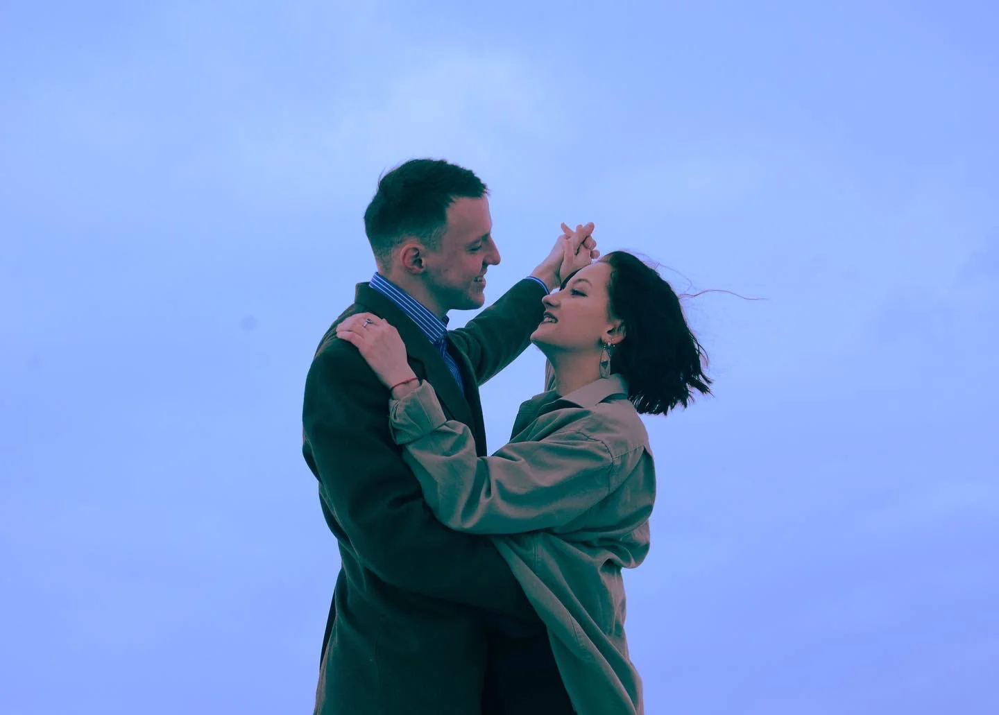 Two people embracing outdoors beneath a blue evening sky
