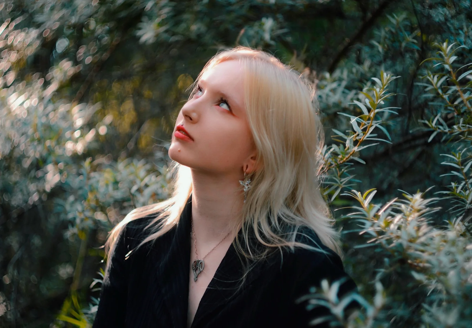 An outdoor portrait in a dark blazer among sunlit leaves