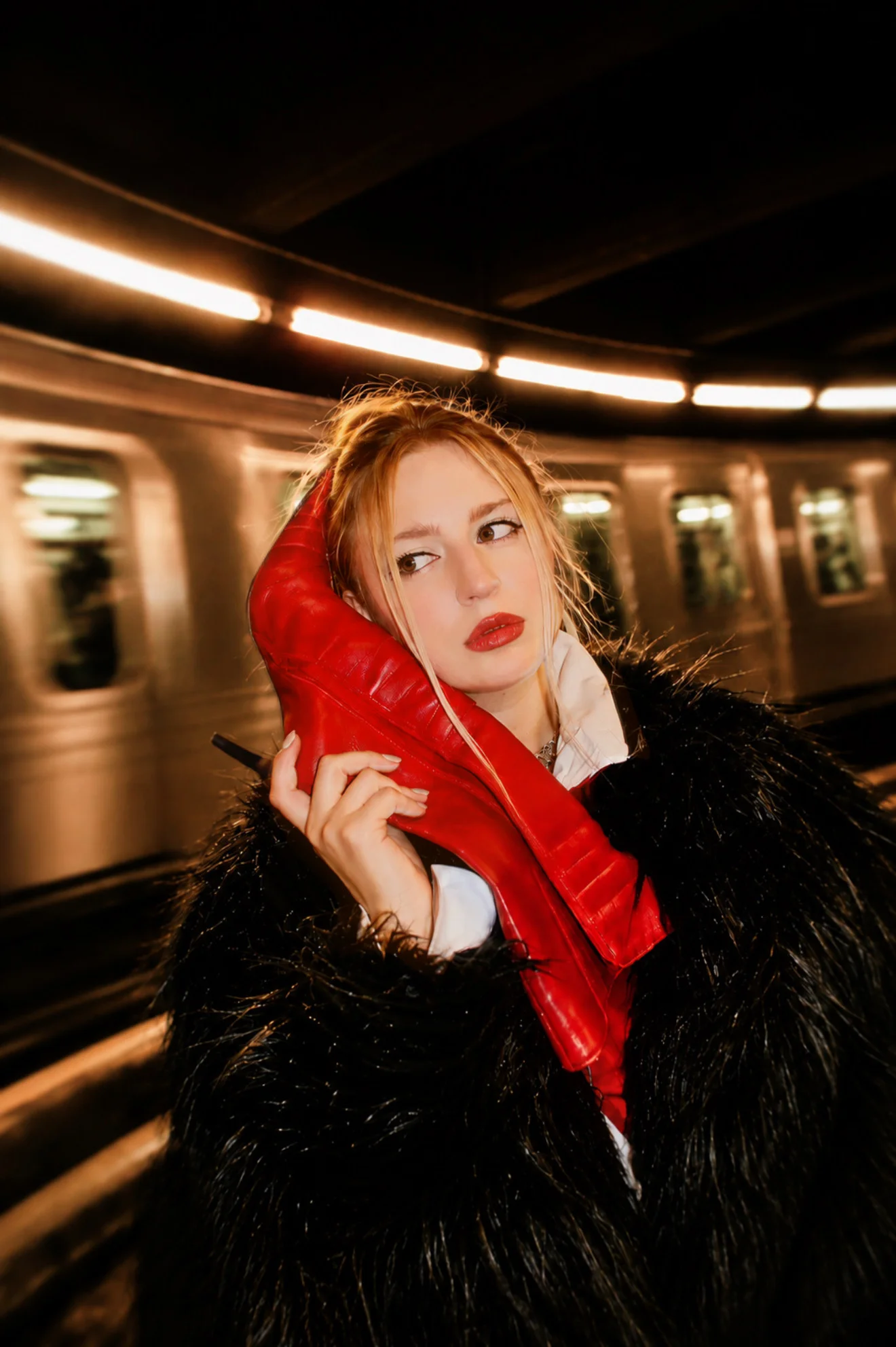 A fashion portrait with a red scarf beside a moving subway train